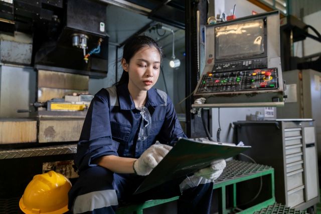 製造業 新規顧客 CNC加工機の前に座る女性